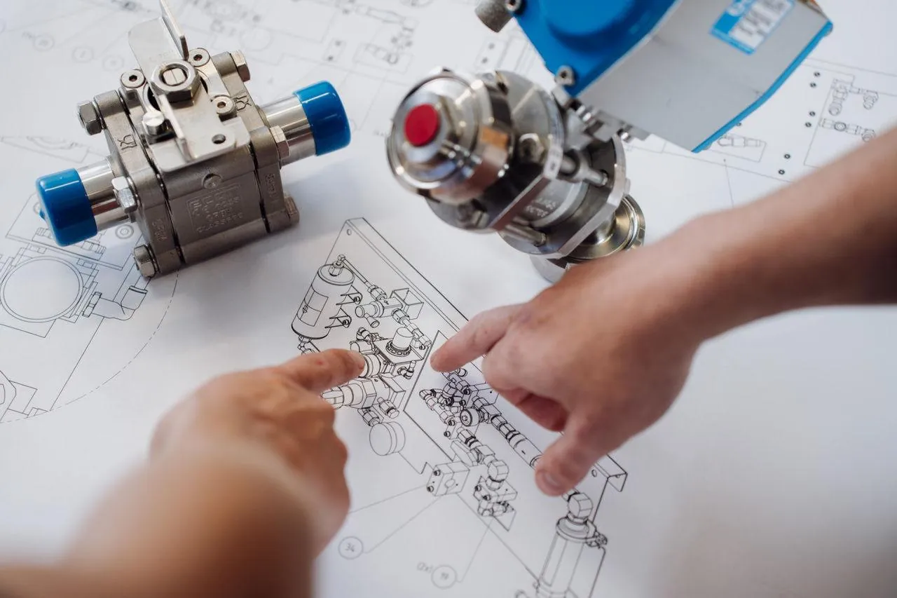 Engineers going through valve drawings next to a valve assembly
